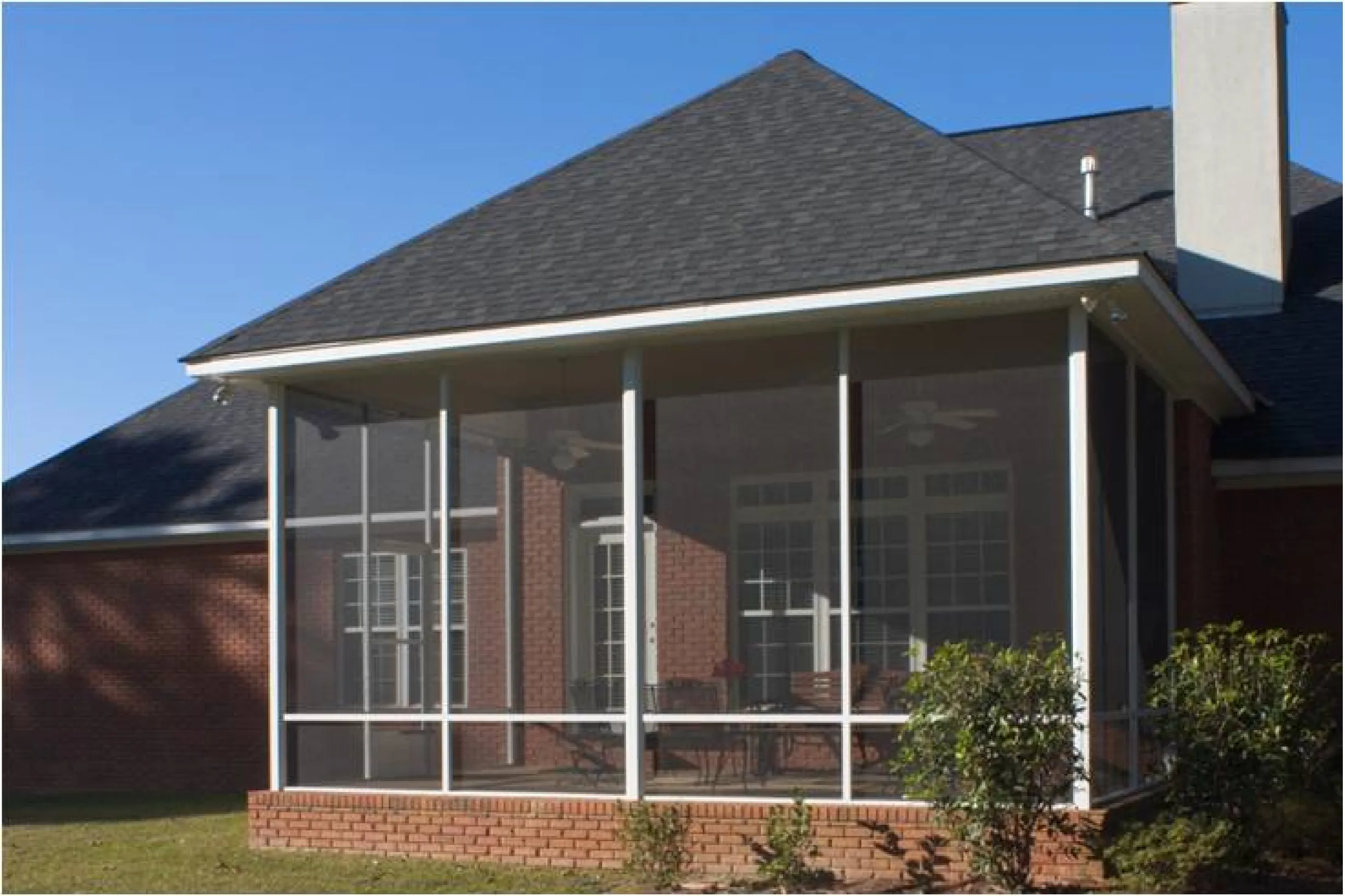 Screened patio enclosure on the back of a brick home