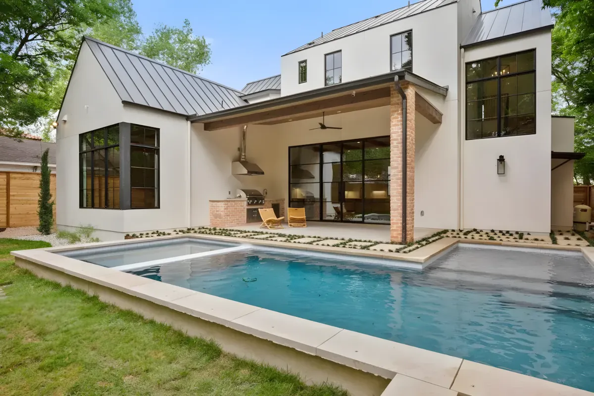 Sun-shelf pool set into a lawn behind a white modern-farmhouse home
