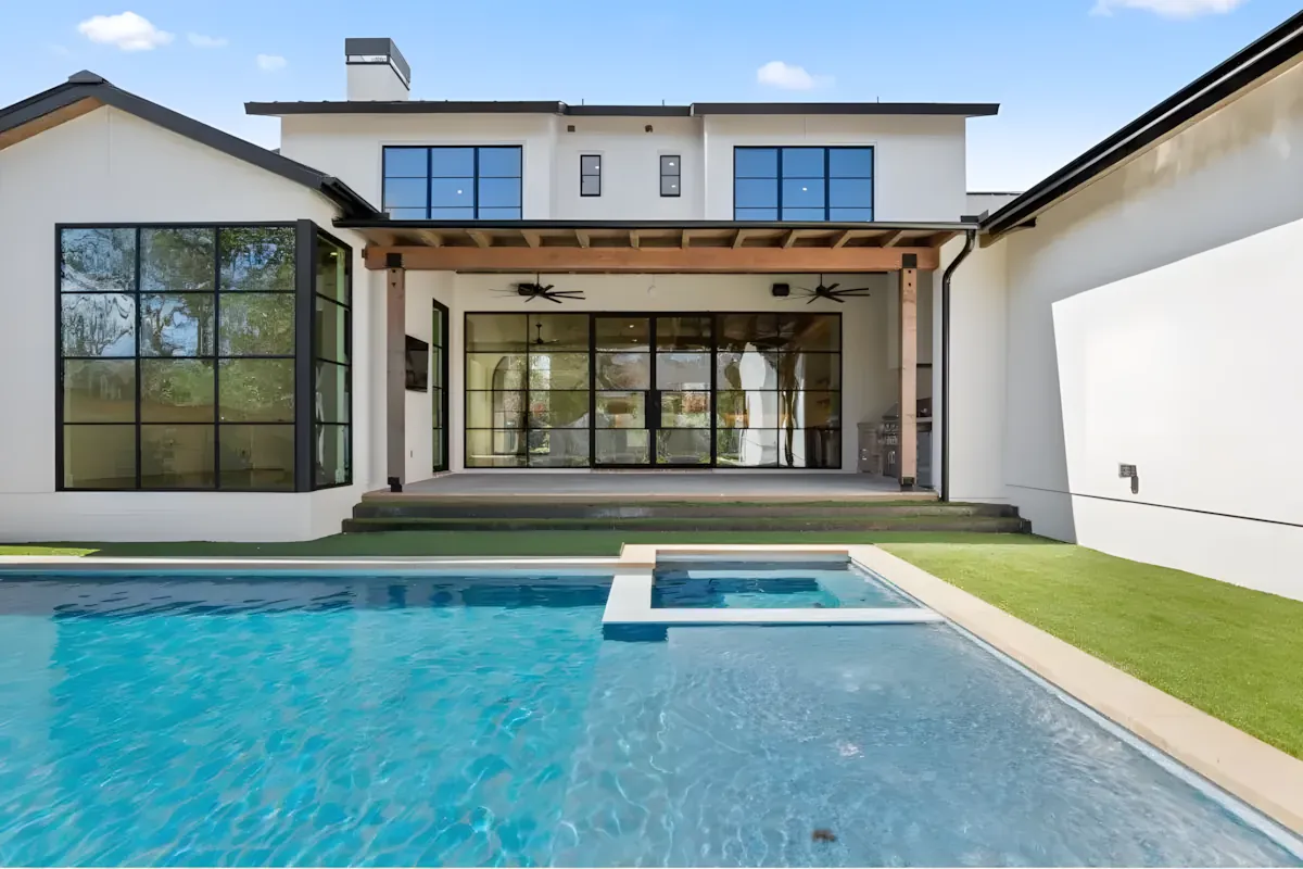 Long lap pool reflecting a modern white home with black steel windows