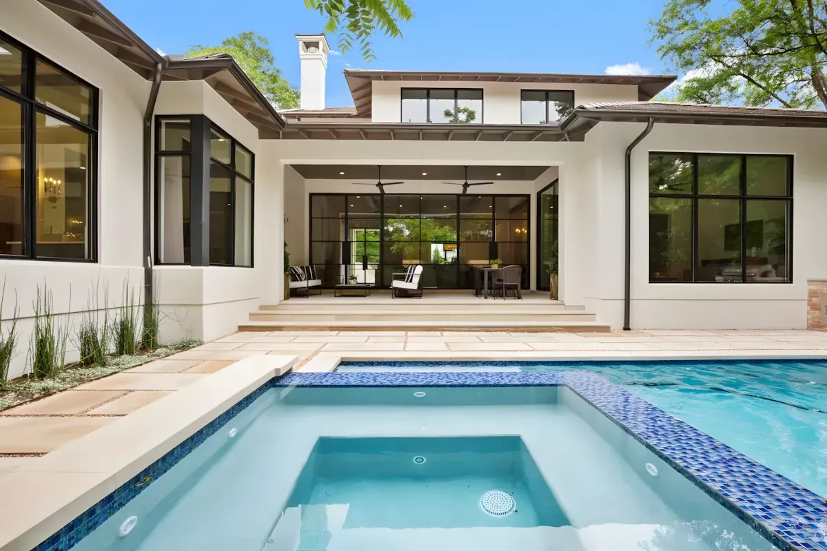 Pool and raised spa framed by limestone paving and ornamental grasses