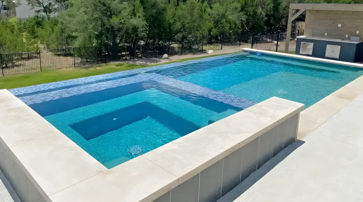 Elevated pool with a spa spillover above a sloping backyard
