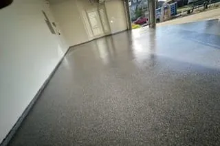 Glossy gray speckled coated concrete floor in an empty garage with white walls