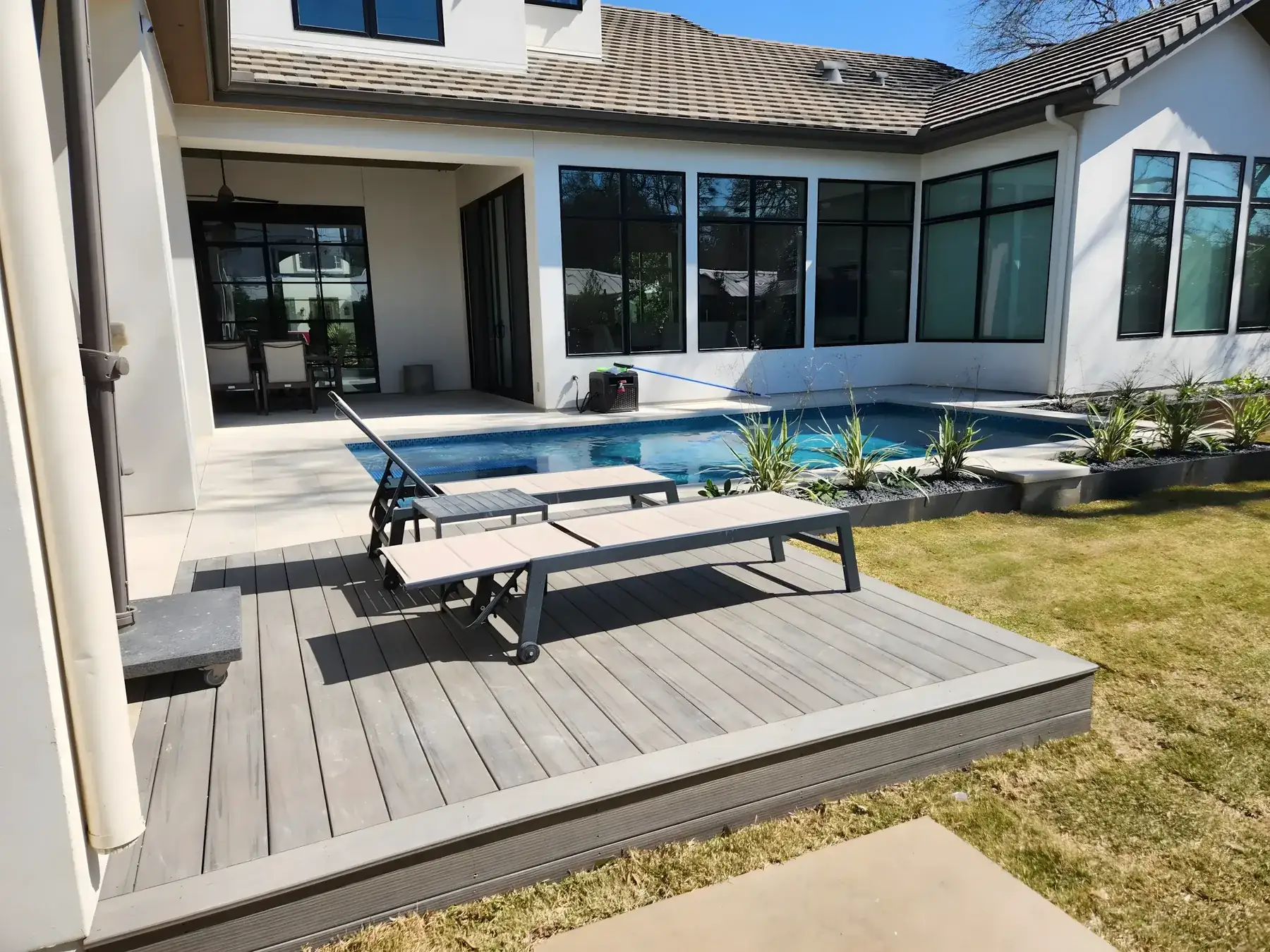 Raised spa spilling into a pool beside a white stucco home