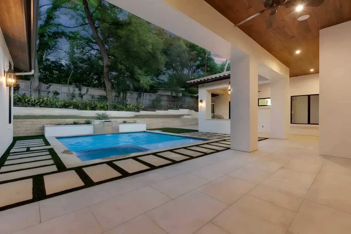 Covered outdoor room with limestone paving stepping down to a pool