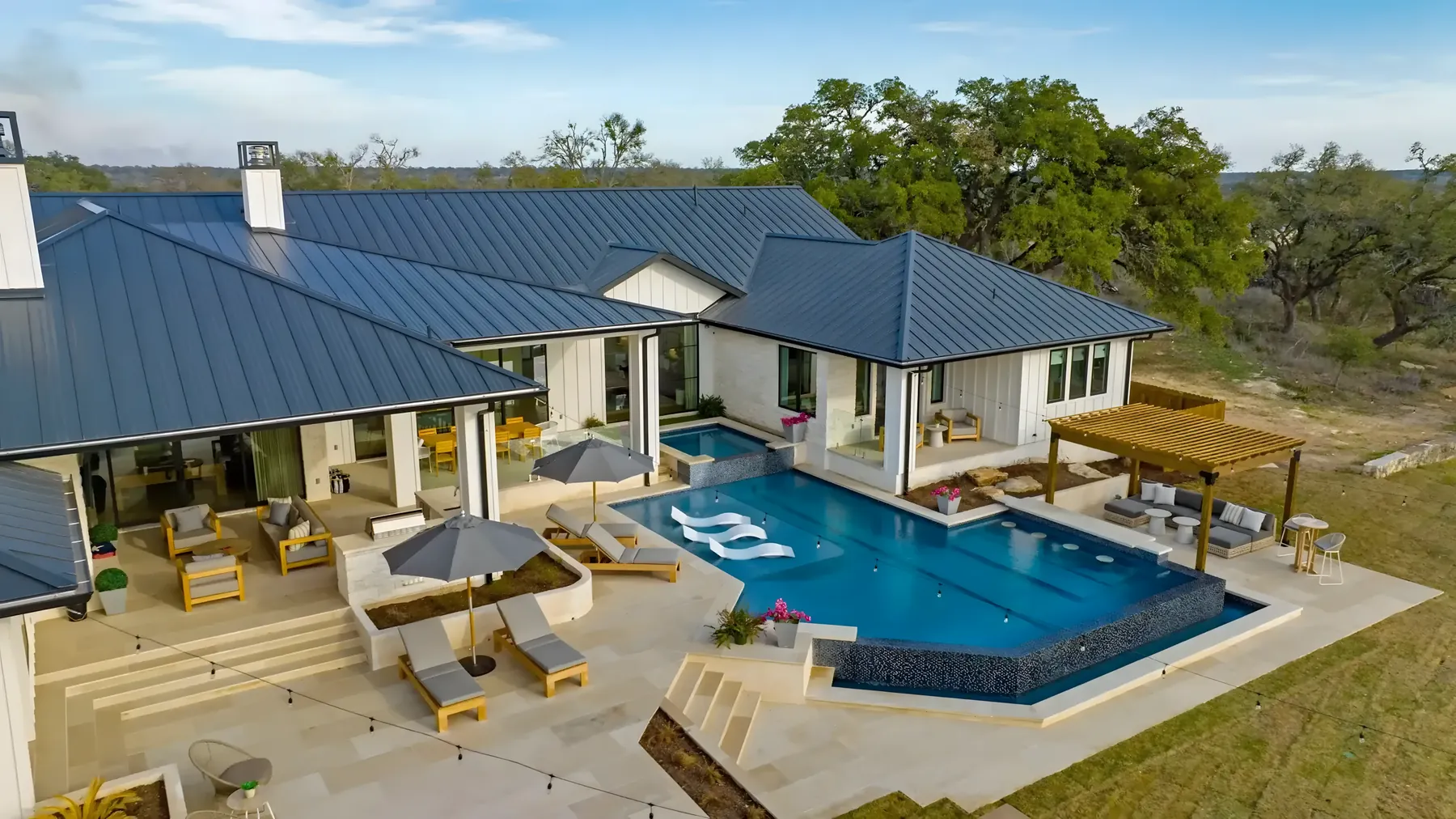 Aerial view of a pool, pergola and shaded lounge terrace