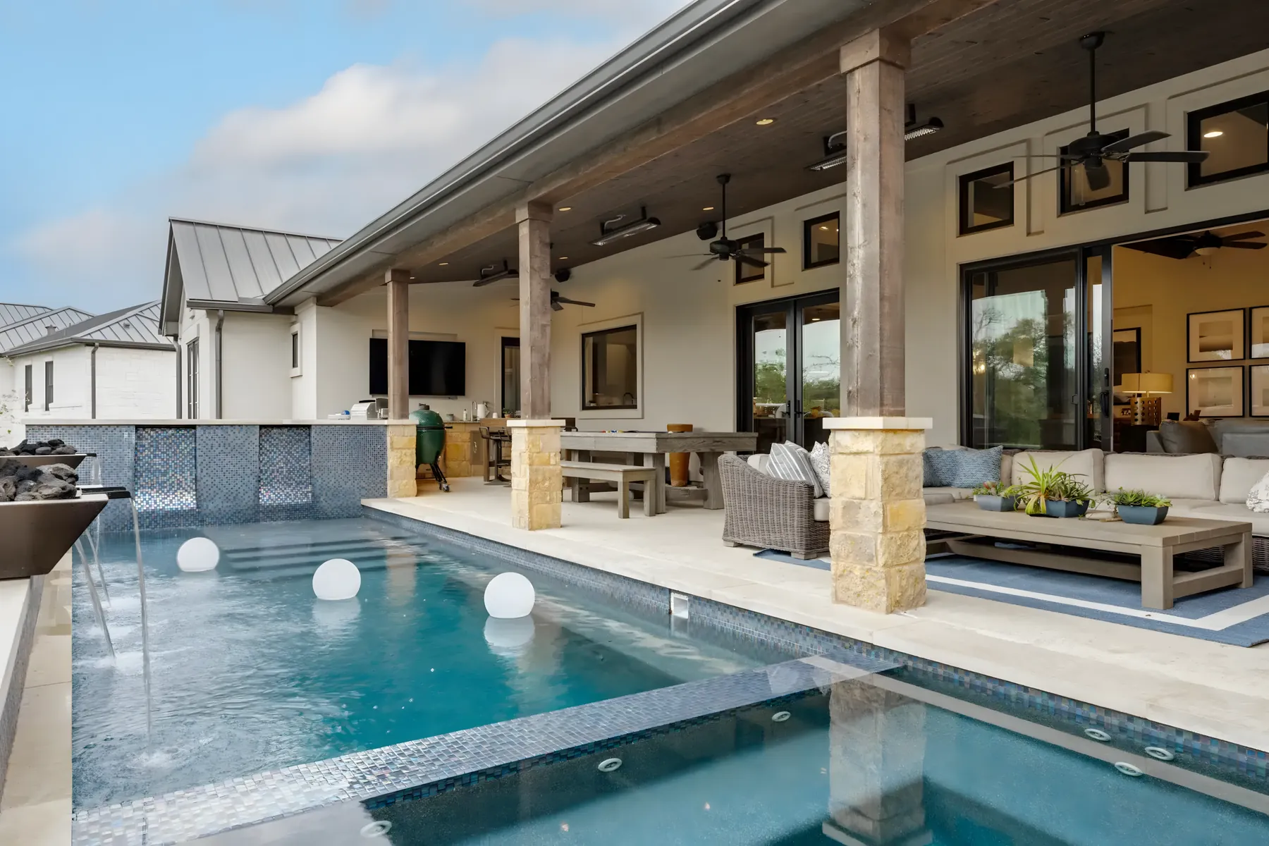 Stone-columned covered patio opening onto a pool at sunset