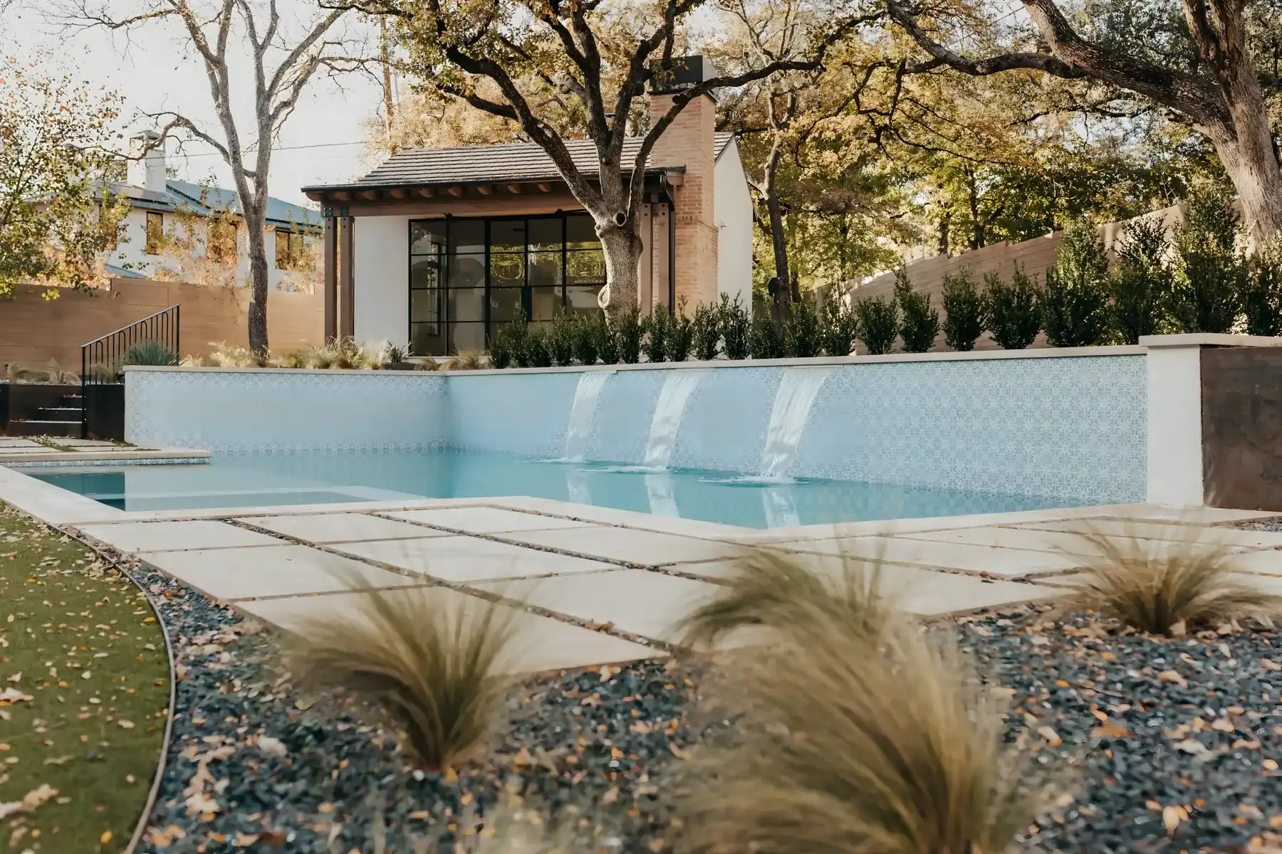 Modern pool with a tiled water wall and ornamental grasses