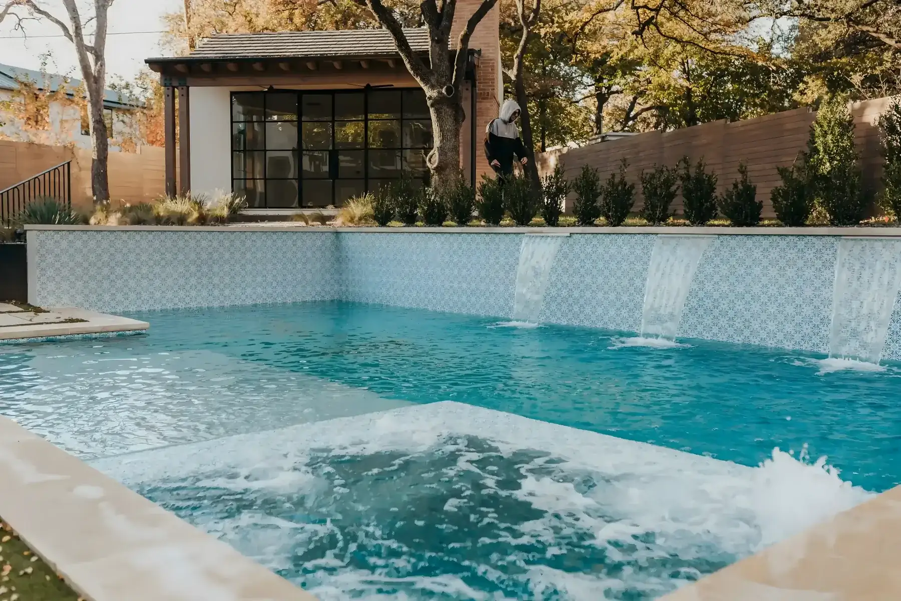 Spa spilling over a tiled wall into a pool below