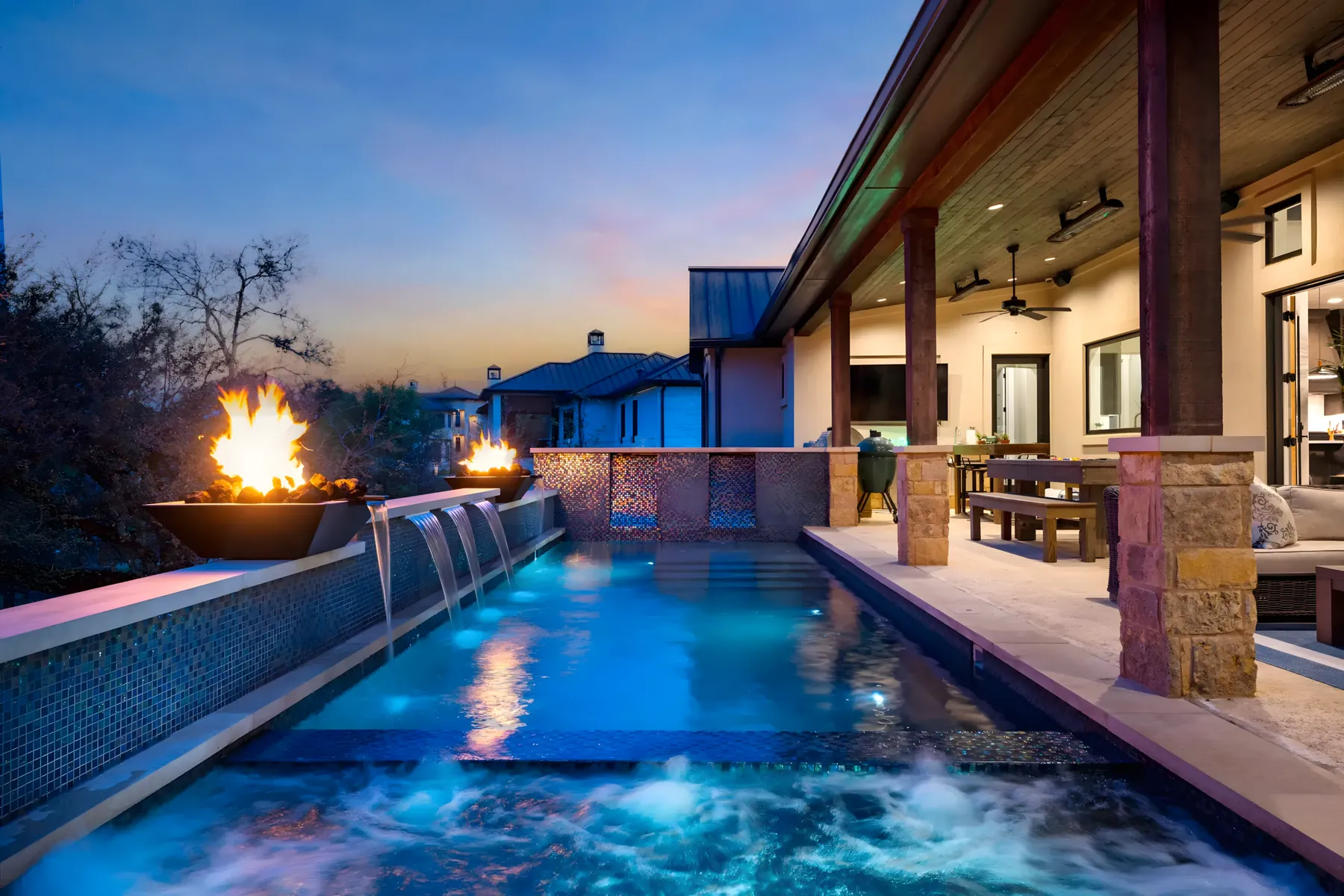 Fire bowls flanking a spa spillover at twilight