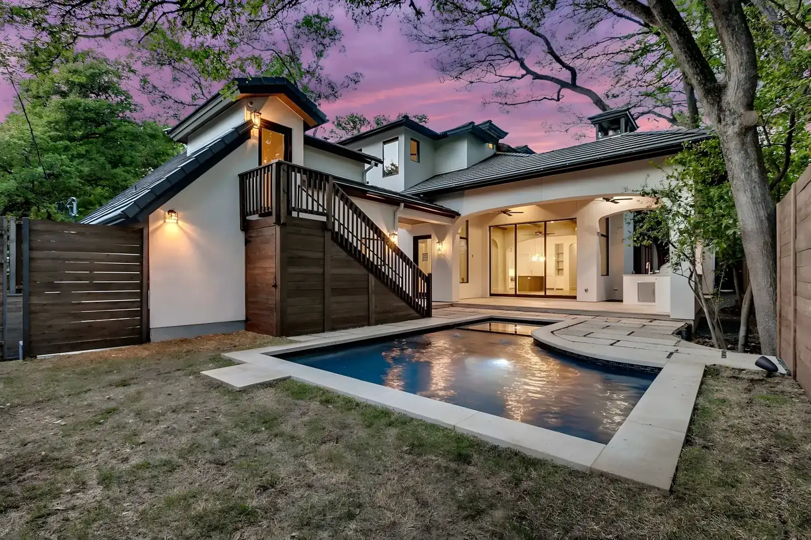 Pool reflecting a home lit against a purple twilight sky