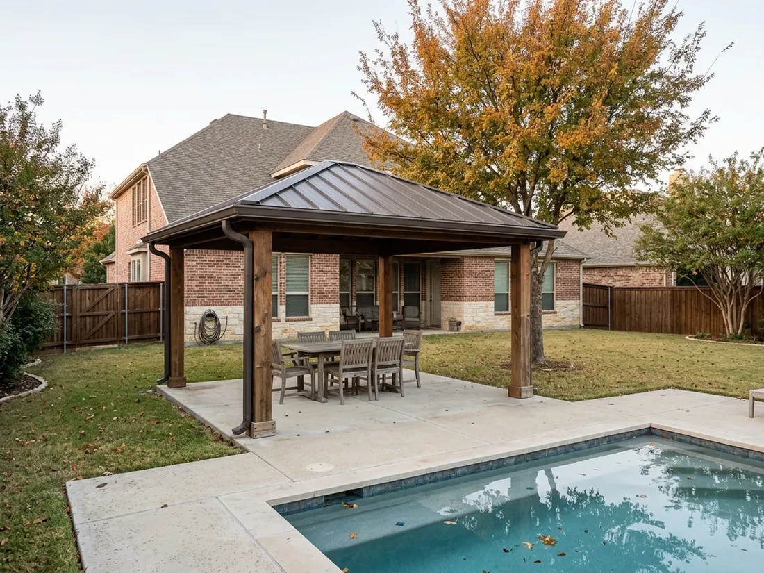 Freestanding patio cover at the far end of a Texas yard beyond a pool
