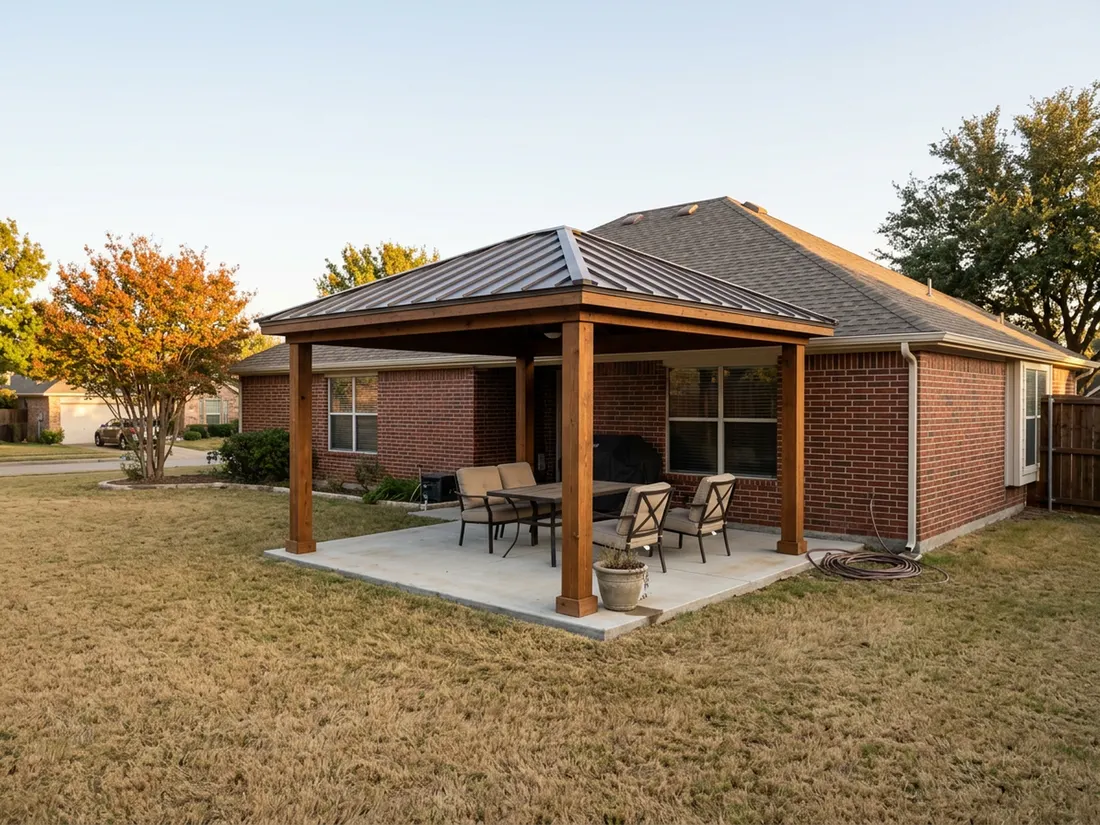 Freestanding cedar and metal patio cover beside a brick Texas ranch house on an autumn afternoon