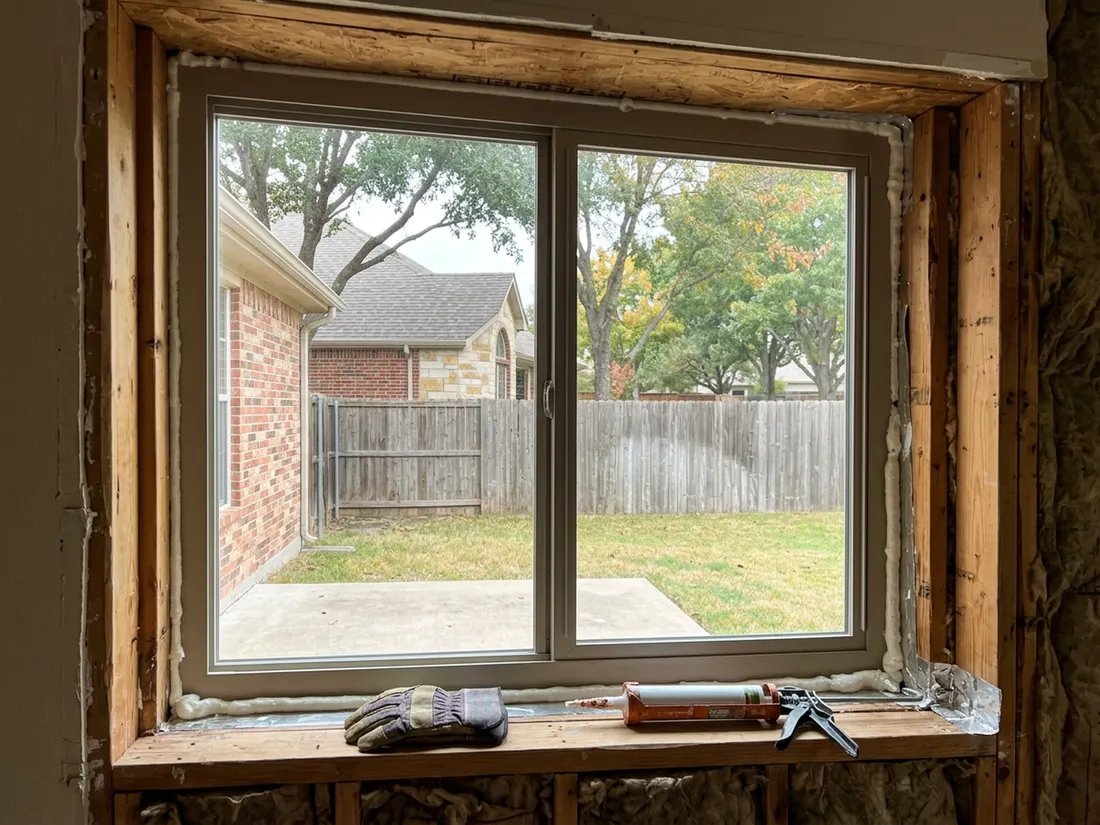 Installer sealing the gap around a new window frame inside a wall opening