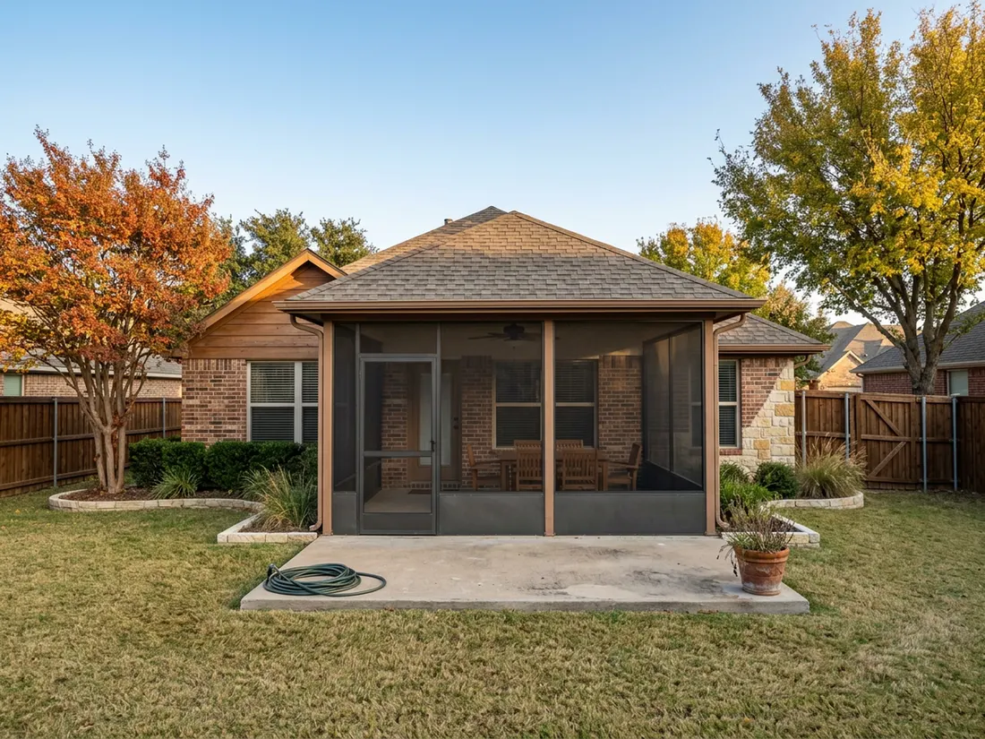 Bronze-framed screen room on a Texas brick home with fall foliage in the backyard