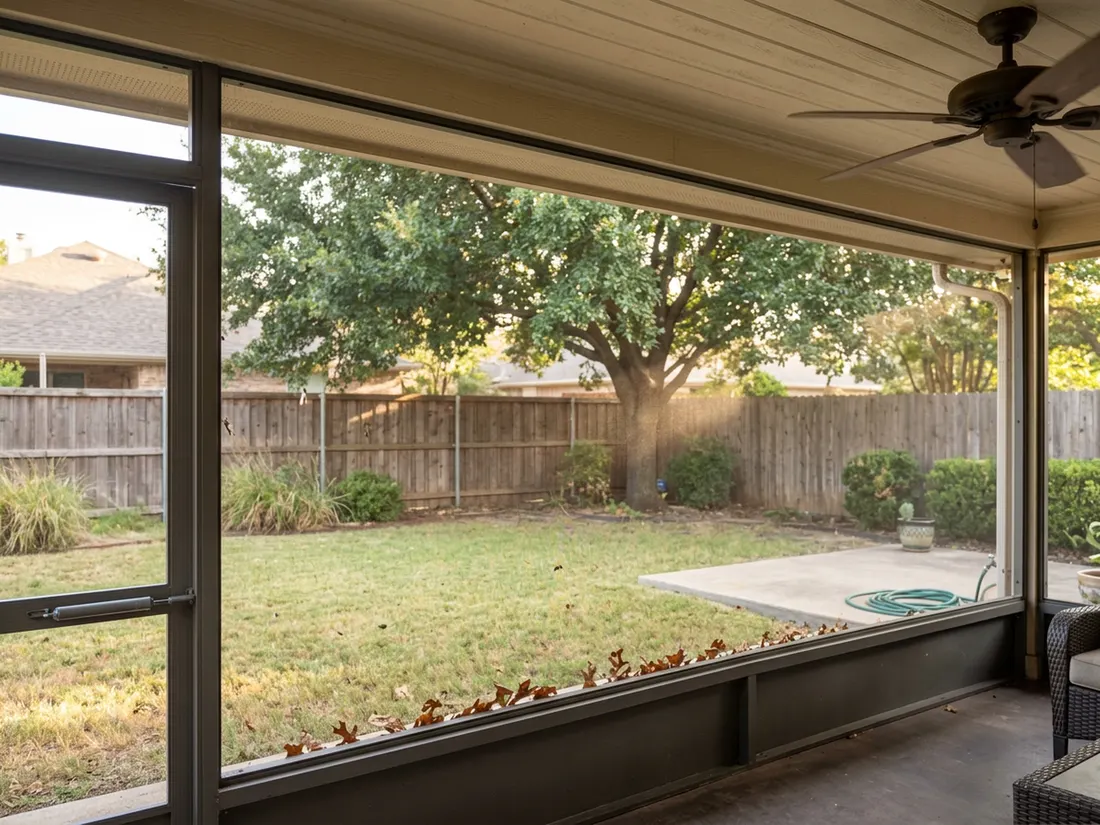 View through dark mesh of a screened patio with ceiling fan and solid roof overhead