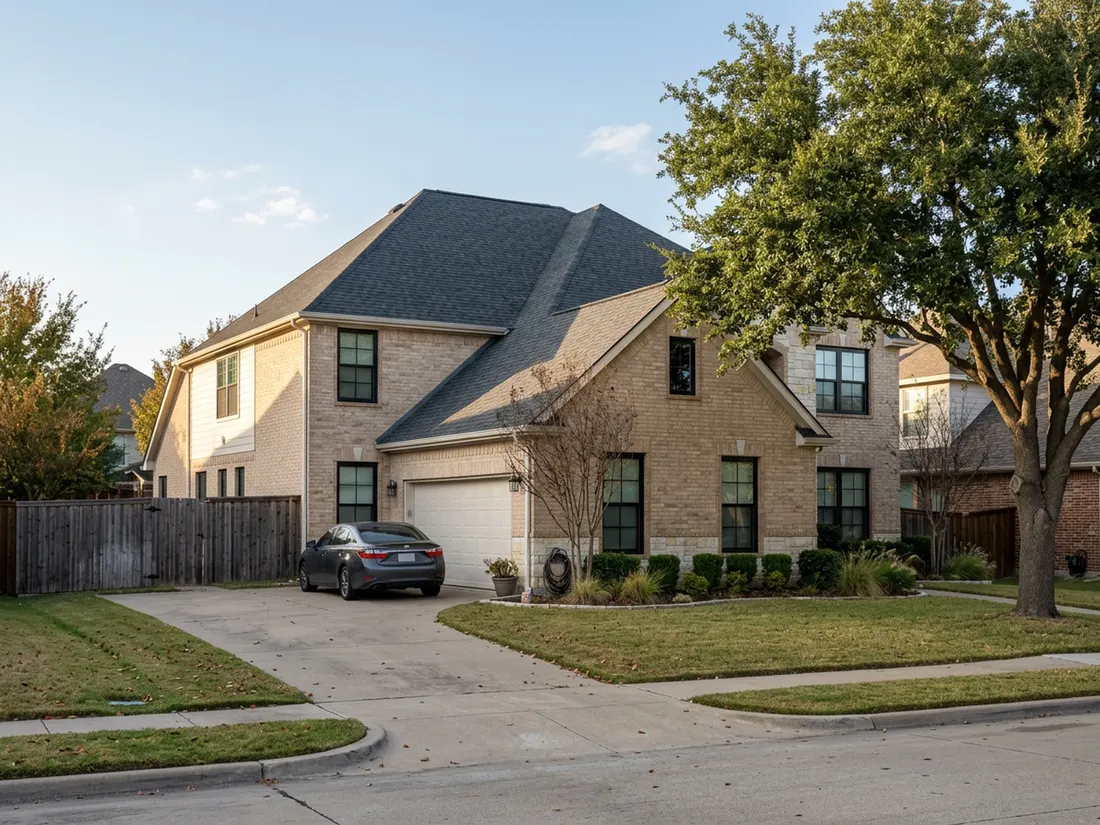 Two-story tan brick home in North Texas with new black-framed double-hung windows and white trim in late afternoon light