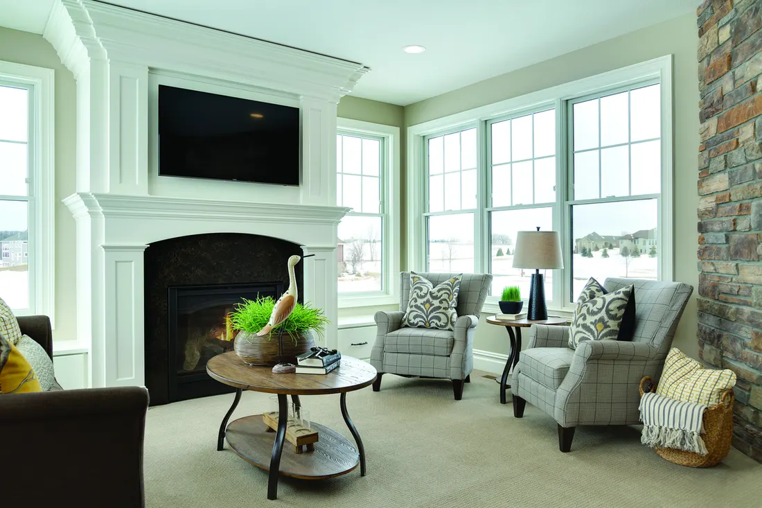 Living room with white grid windows beside a white fireplace mantel and armchairs