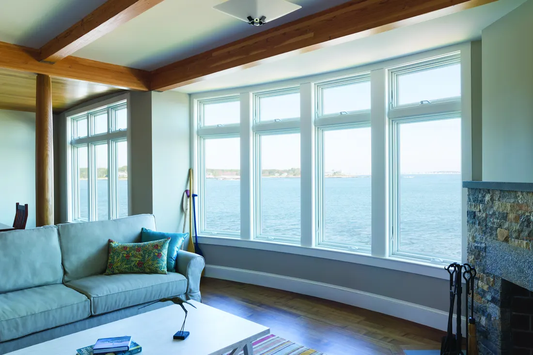 Large white-framed picture windows in a living room overlooking the ocean