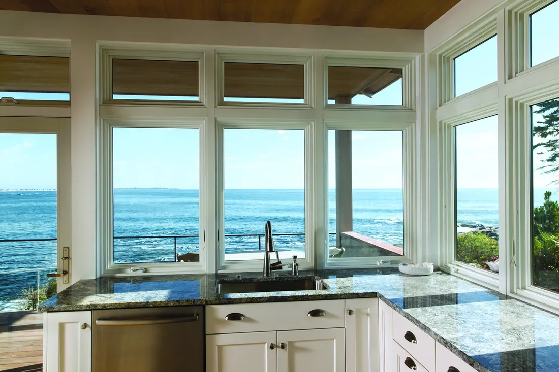 White trimmed windows over granite kitchen counters overlooking a wide blue ocean