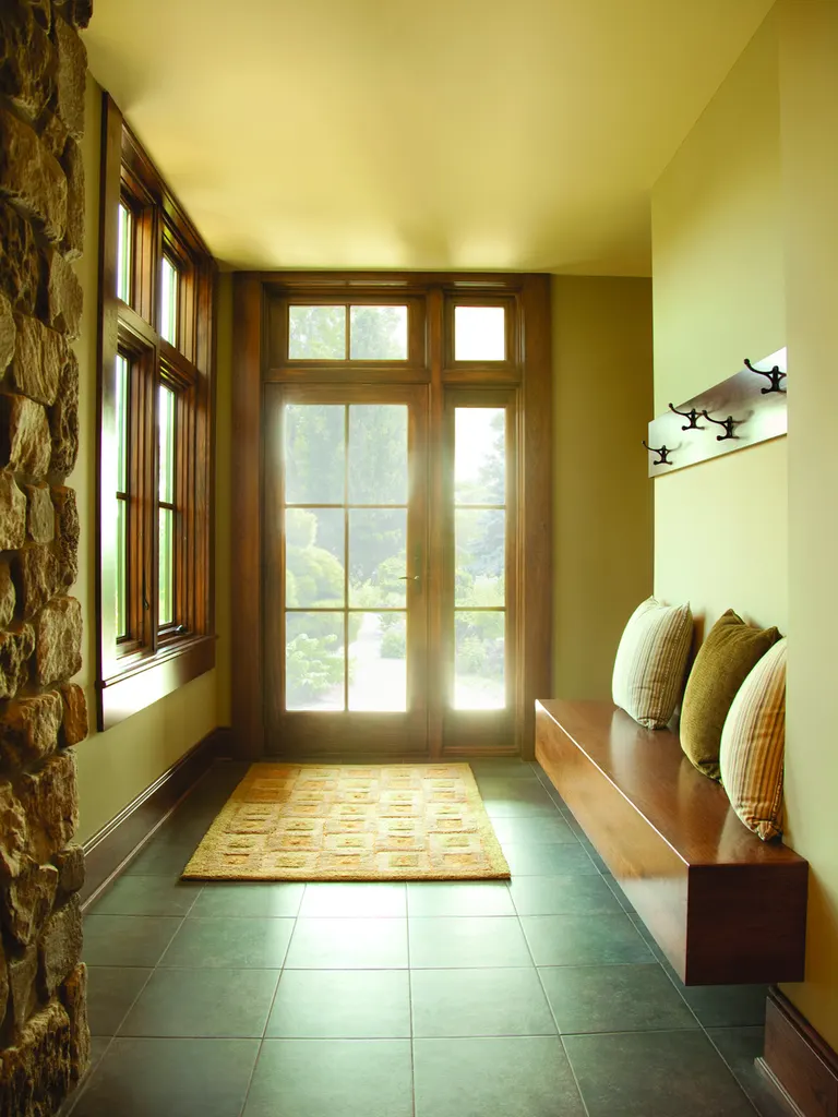 Wooden French door with glass panes and transom window in a sunlit entryway