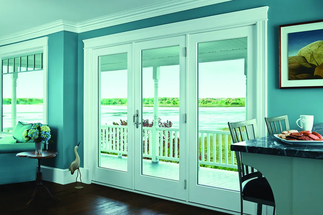 White framed glass patio doors and window in a teal room overlooking a lake