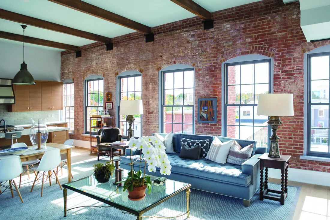 Row of arched multi-pane windows set into an exposed red brick wall inside an apartment loft