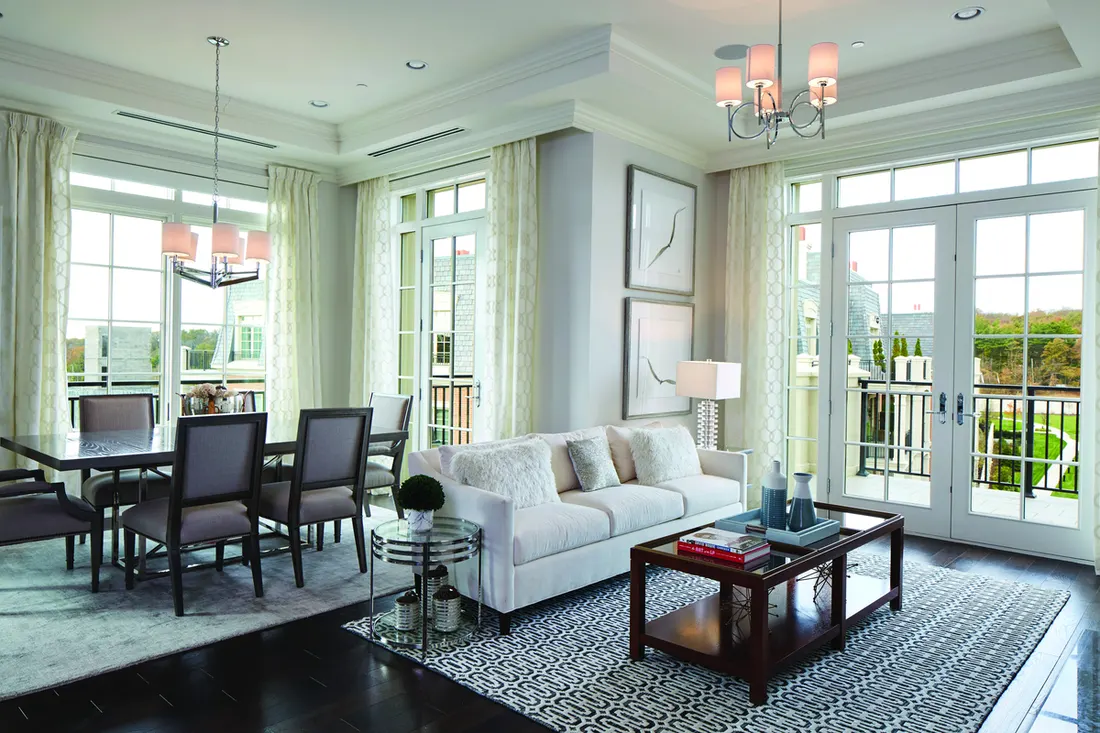 Living room with large white-framed gridded windows, French doors, dark hardwood floors, and light furniture