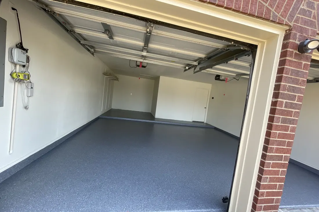 Spacious empty garage interior featuring a smooth gray speckled coated concrete floor and white walls