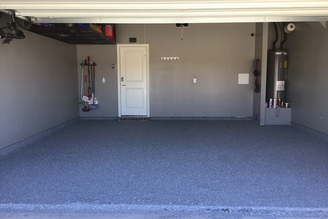 Empty residential garage with a grey speckled epoxy coated concrete floor and grey walls