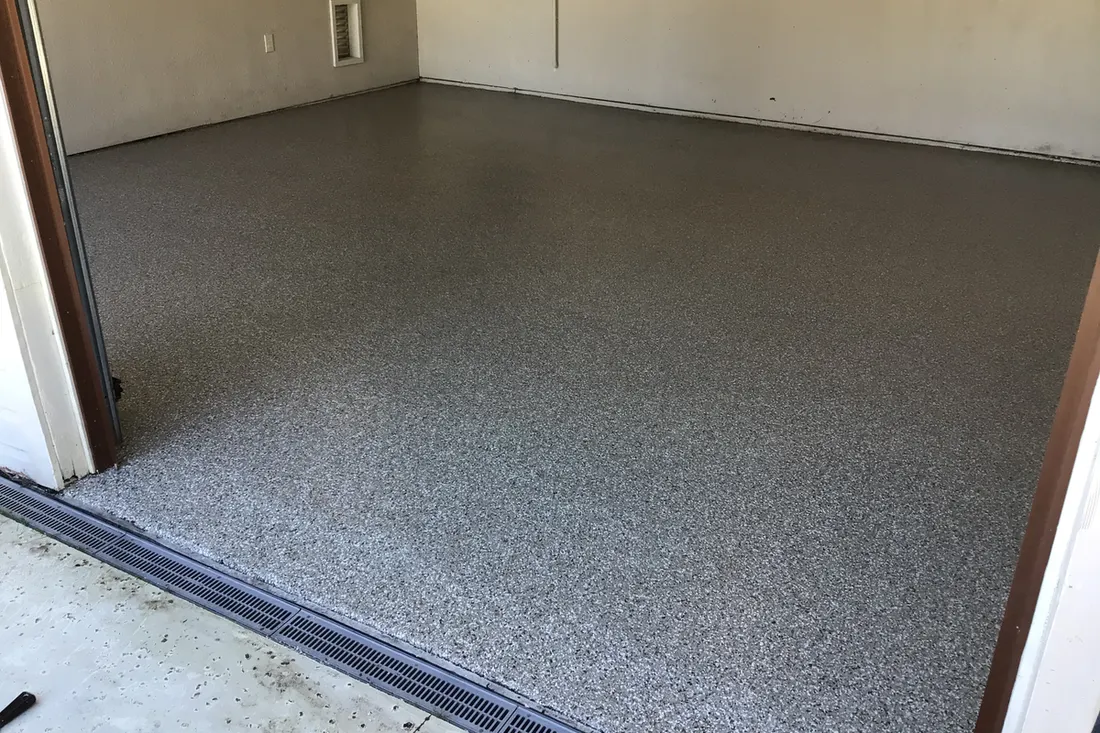 Empty garage interior featuring a smooth gray speckled epoxy coated concrete floor