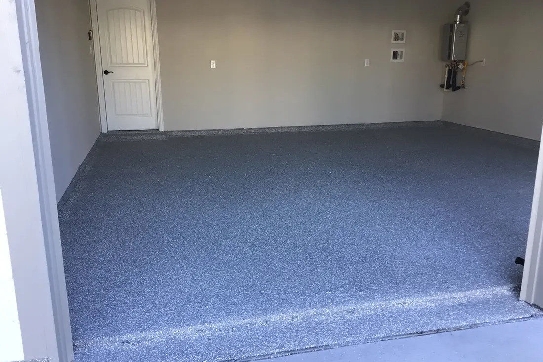 Empty garage interior featuring a gray speckled concrete coating floor and light beige walls