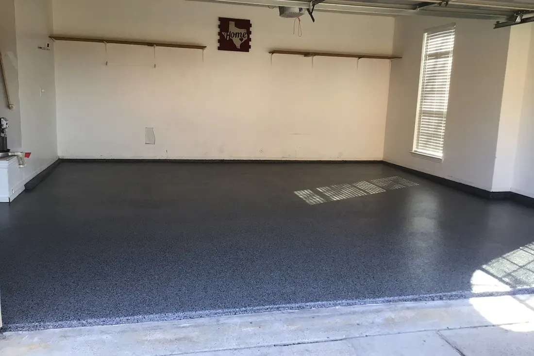 Dark gray speckled concrete coating on a clean floor inside an empty two-car garage