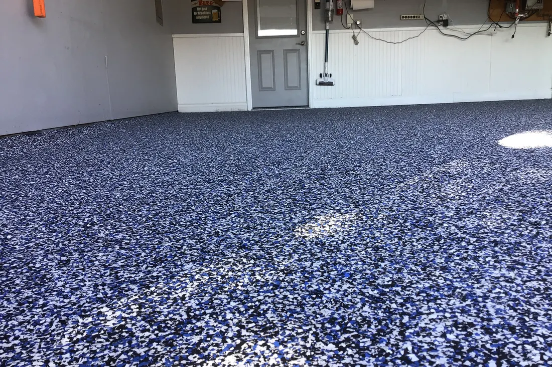 Garage floor coated with blue, black, and white speckled epoxy flake finish