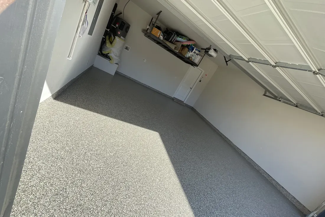Spacious residential garage interior featuring speckled gray coated concrete floors and white walls