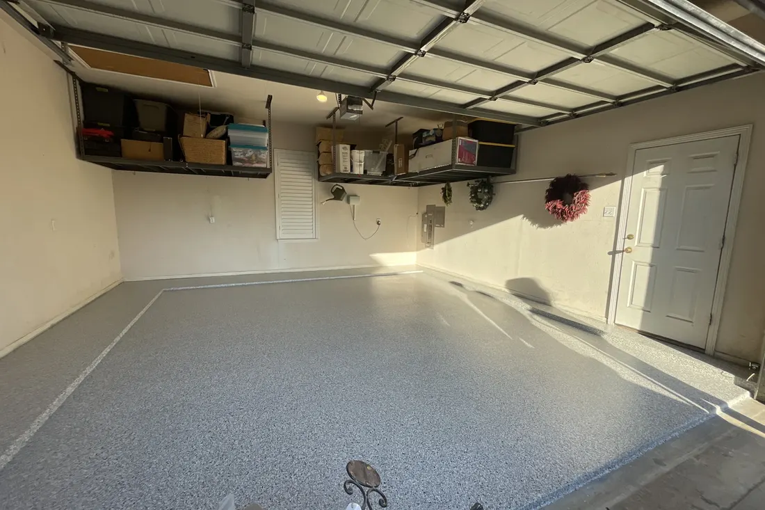 Glossy gray speckled coated concrete floor inside an empty two-car residential garage