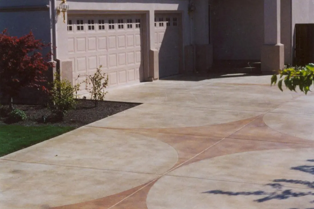Decorative coated concrete driveway with tan and brown geometric patterns outside a residential garage