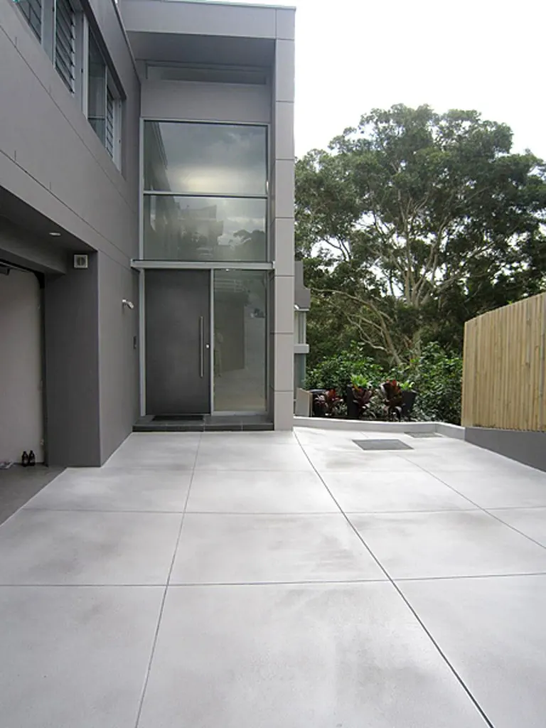 Smooth light gray concrete driveway coating outside a modern gray home entrance