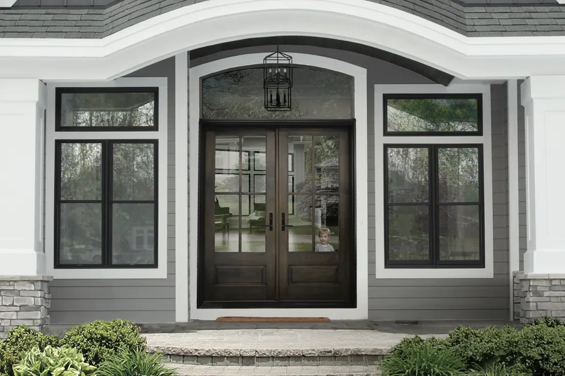 Dark brown double entry doors with glass panes, transom window, and gray exterior siding