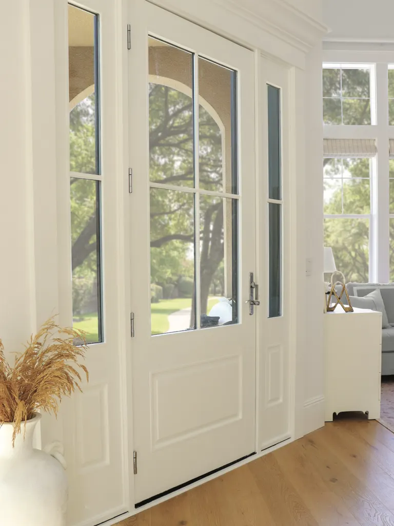 White entry door with divided glass panes and matching sidelights in a bright foyer