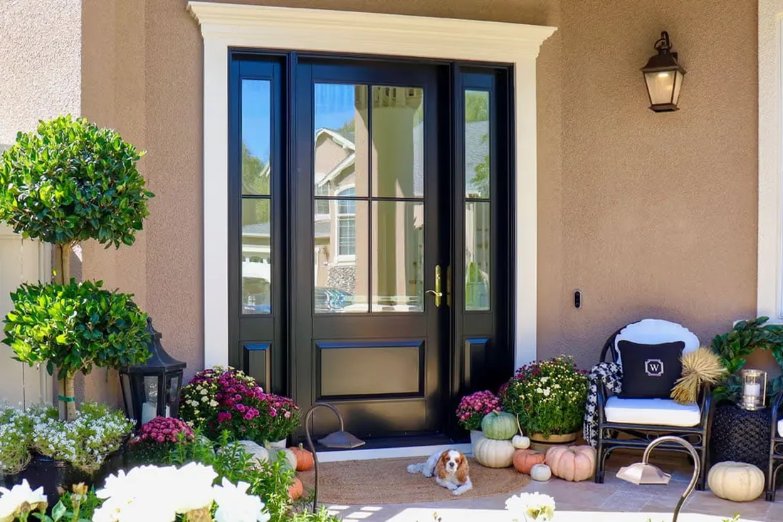 Black front entry door with glass panes and sidelights framed by white trim on porch
