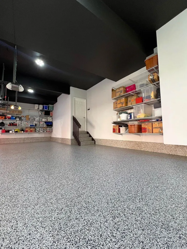 Speckled gray epoxy floor coating across a garage with white walls and black ceiling