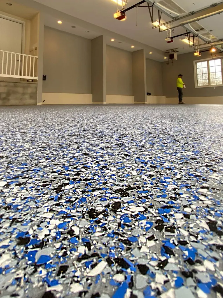 Blue, black, and white speckled flake epoxy coating on a spacious garage concrete floor
