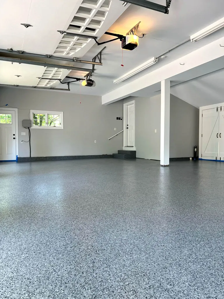 Spacious garage interior featuring a glossy gray speckled epoxy coated concrete floor