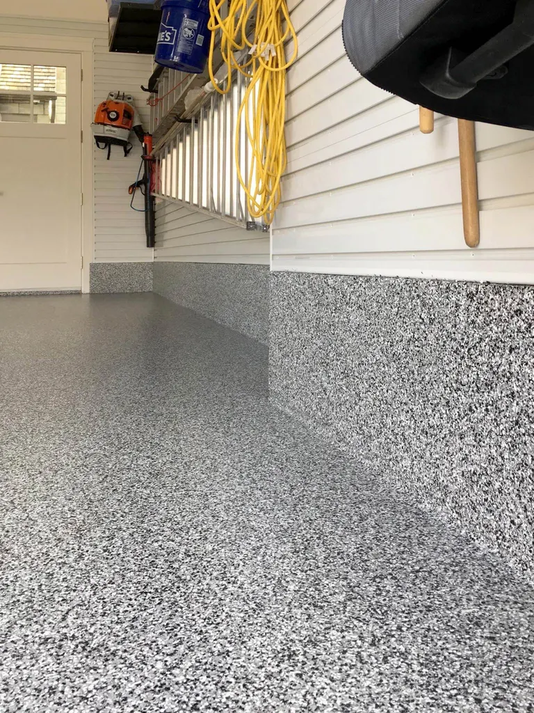 Speckled gray epoxy coating on a garage floor and along the lower wall baseboard