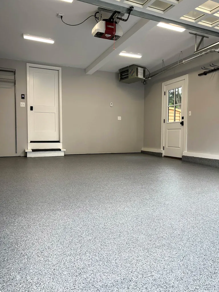 Gray speckled flake coated concrete floor in a garage with white doors