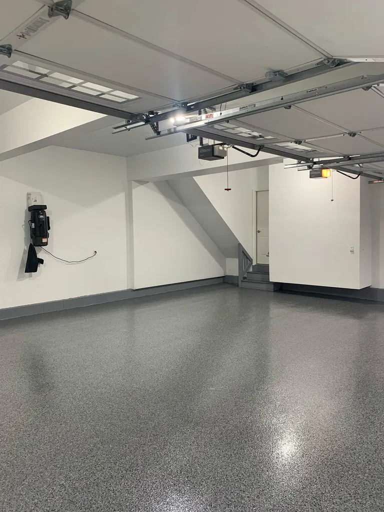 Spacious residential garage interior featuring glossy gray speckled coated concrete floor and white walls