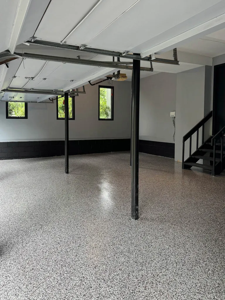 Glossy gray flake garage floor coating with black support poles and stairs