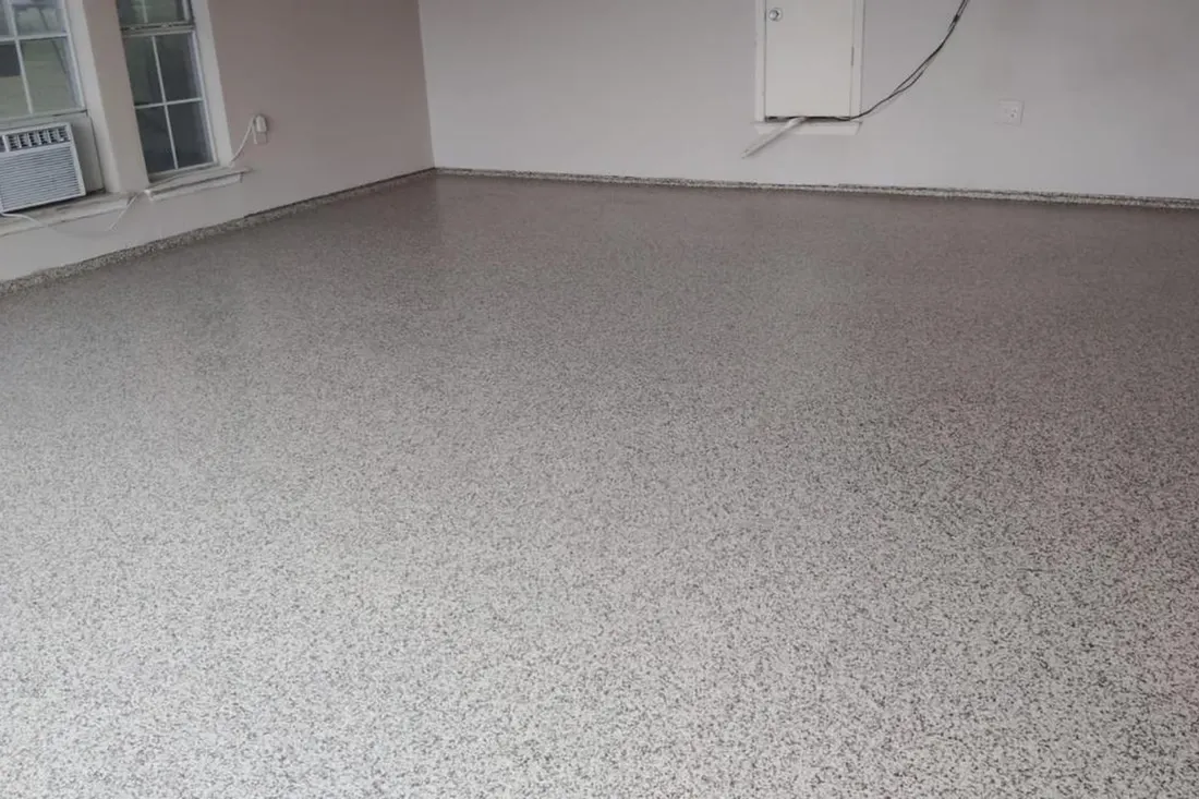 Empty garage with gray speckled flake coating on the floor and plain white walls