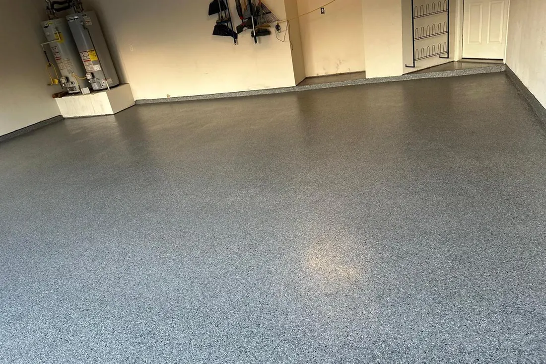 Glossy gray speckled coated floor in an empty residential garage with neutral walls