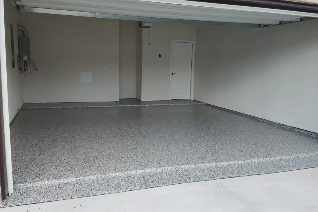Gray speckled flake coating on an empty residential garage floor with white walls